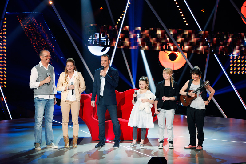 Sarkis Ohanessian, en jeans-bleu, veston bleu et chemise blanche, est sur le plateau de Un Air de Famille, émission produite de 2013 à 2016 par la RTS. Il est entouré de la famille Mojon.
