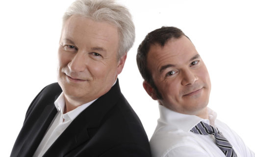 Sarkis Ohanessian et Philippe Robin, animateurs du Grand Quiz et son bêtisier 2009 à la Radio Télévision Suisse. Sarkis porte une chemise blanche et une cravate lignée de noir et gris. Les deux animateurs sont dos à dos et regardent l'objectif.