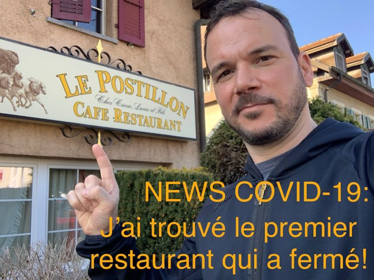 Selfie de Sarkis Ohanessian, habillé d'un sweat à capuche noir. Sarkis Ohanessian montre l'enseigne d'un café-restaurant qui s'appelle "Le Postillon". Sur la photo, il est écrit en orange en surimpression "News-Covid-19: j'ai trouvé le premier restaurant qui a fermé!"