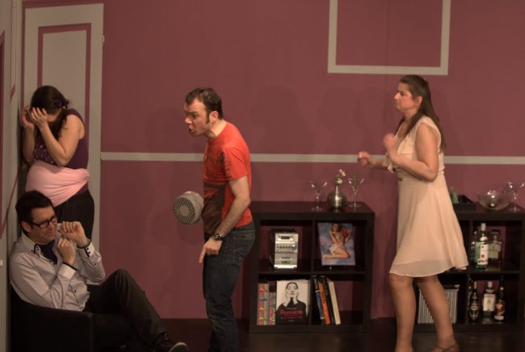 Sarkis Ohanessian est sur la scène du Théâtre le Caveau dans la pièce "Gros mensonges" de Luc Chaumar. Il est avec Estelle Zweifel, Christian Baumann et Julie Despriet. Il est vêtu d'un jeans noir et d'un t-shirt rouge.