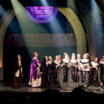 Sarkis Ohanessian est sur la scène du Théâtre Barnabé de Servion dans "Sister Act". Il est vêtu de blanc et de paillettes violettes. Il est avec les nonnes dans la scène de la revue de presse.