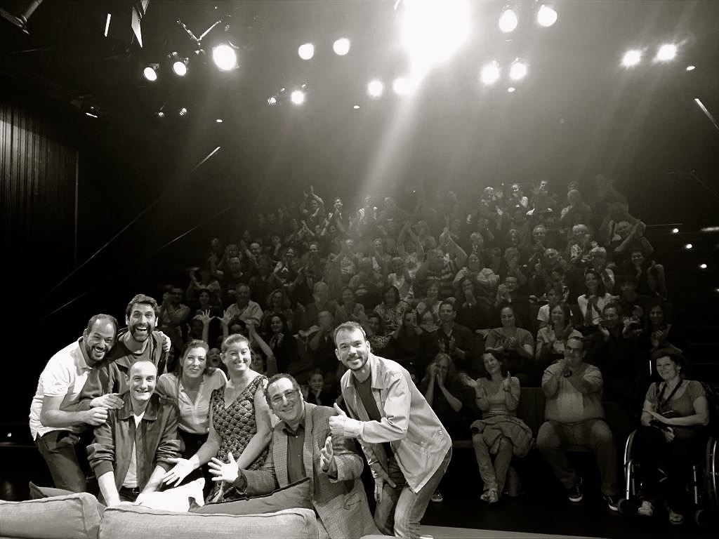 Selfie en noir et blanc des comédien de "Stationnement alterné" de Ray Cooney au Théâtre le Douze Dix-huit. Les comédiens, Sarkis Ohanessian, Julie Despriet, Laurent Baier, Fausto Borghini et Christian Baumann sont tout sourire et on aperçoit le public derrière qui applaudit.