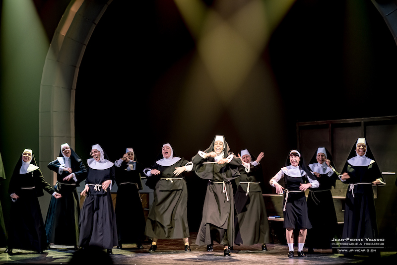Les nonnes de Sister Act au théâtre Barnabé de Servion chantent et dansent sur la scène. Elles sont toutes habillées de soutanes noires.